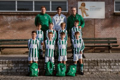 Foto van de spelers van de AWC JO9-4, in AWC tenue, met trainers